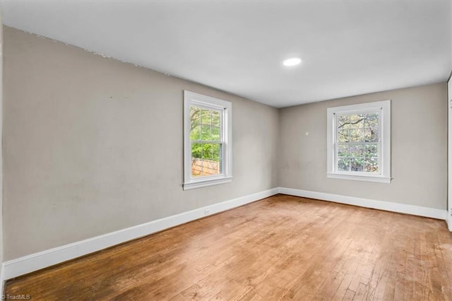 empty room featuring wood-type flooring, baseboards, and recessed lighting