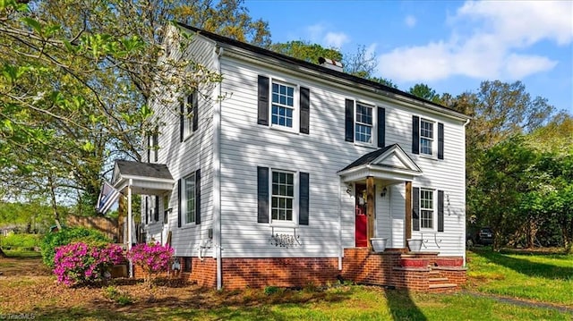 colonial house featuring a chimney and a front lawn