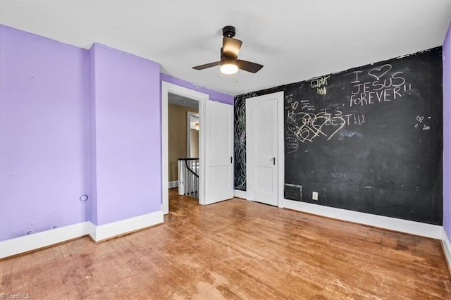 unfurnished room featuring baseboards, a ceiling fan, and wood finished floors