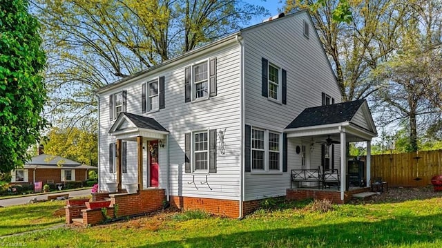 colonial-style house with a front yard, a porch, and fence