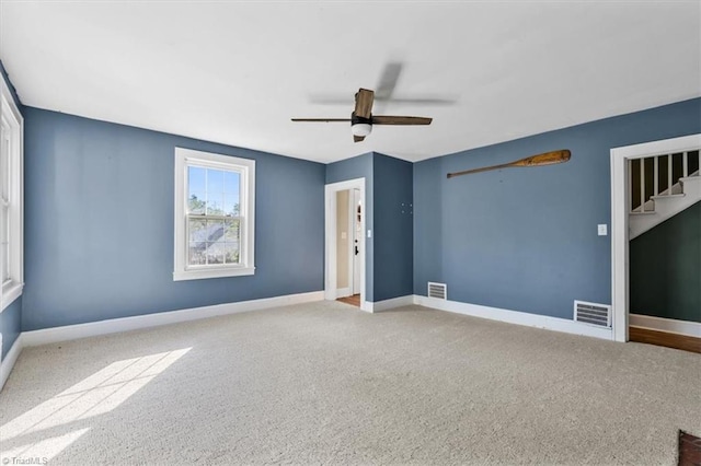 carpeted spare room featuring visible vents, baseboards, and a ceiling fan