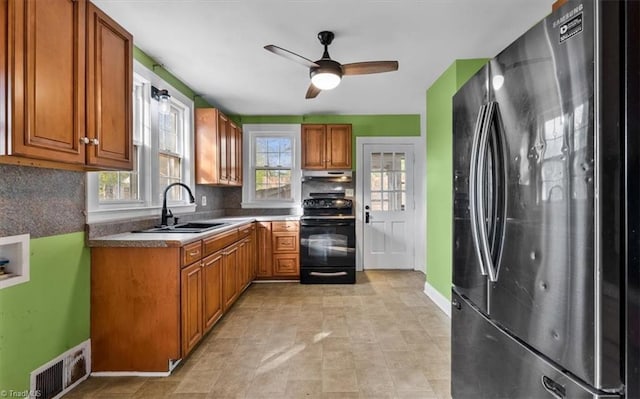kitchen featuring freestanding refrigerator, visible vents, under cabinet range hood, black electric range, and a sink