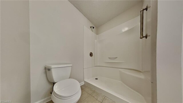 full bath with a shower, tile patterned flooring, toilet, baseboards, and a textured ceiling