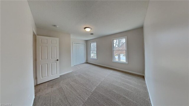 carpeted spare room with baseboards and a textured ceiling