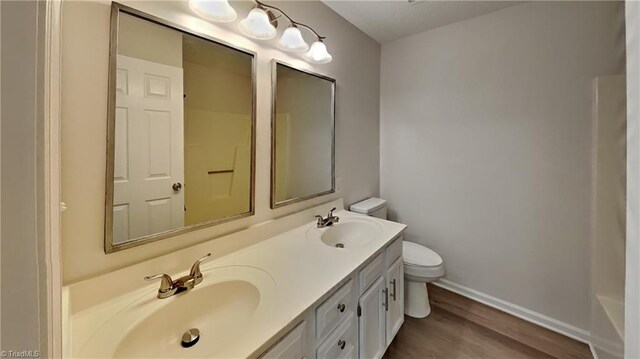 bathroom featuring baseboards, double vanity, a sink, and toilet