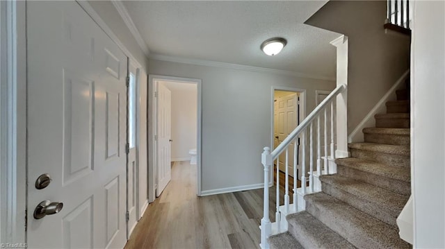entryway with crown molding, baseboards, stairs, and wood finished floors