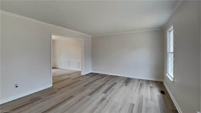 empty room with visible vents, crown molding, baseboards, and wood finished floors