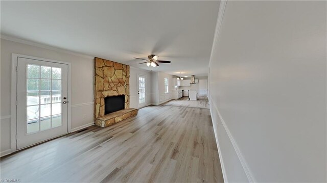 unfurnished living room with light wood-type flooring, baseboards, a fireplace, and ceiling fan