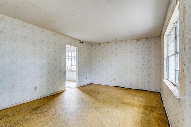 empty room with visible vents, wallpapered walls, and tile patterned floors