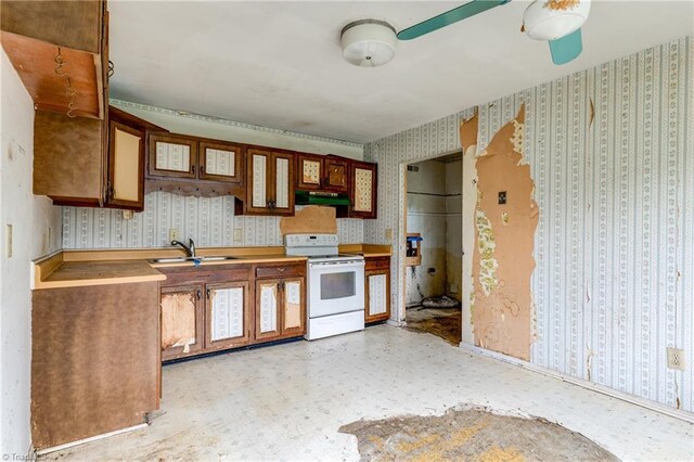 kitchen featuring light floors, wallpapered walls, under cabinet range hood, a sink, and electric range