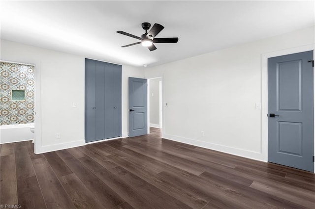 unfurnished bedroom with ensuite bath, dark wood-type flooring, and ceiling fan