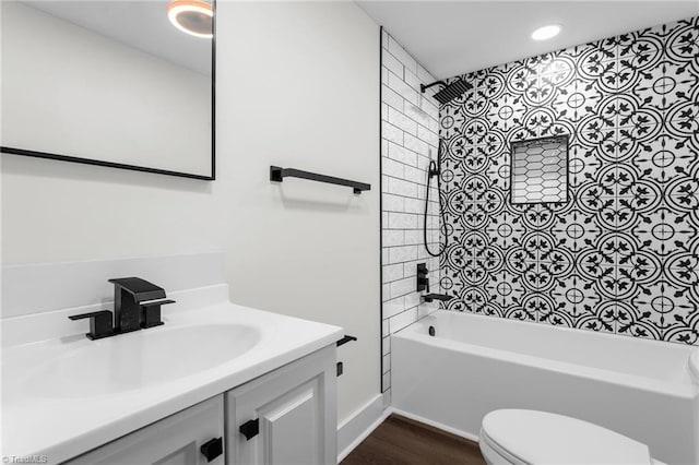 full bathroom with tiled shower / bath combo, vanity, hardwood / wood-style flooring, and toilet