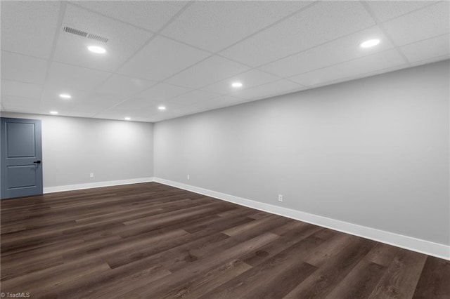 empty room with dark hardwood / wood-style flooring and a drop ceiling