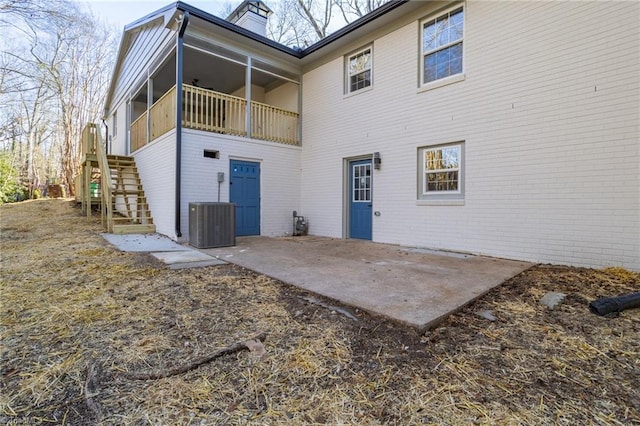 rear view of property with a sunroom, central AC unit, and a patio area