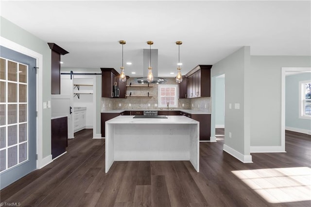 kitchen featuring sink, decorative backsplash, hanging light fixtures, a center island, and a barn door