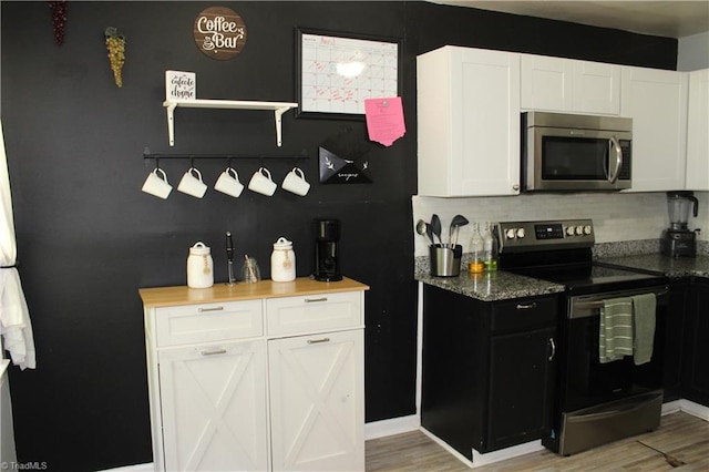 kitchen featuring light wood finished floors, white cabinetry, stainless steel appliances, and decorative backsplash