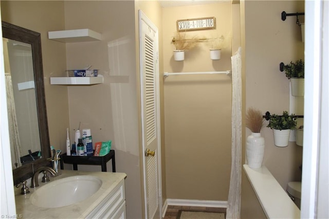 bathroom featuring a closet, toilet, and vanity