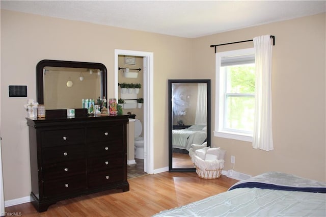 bedroom featuring light wood-type flooring, ensuite bathroom, and baseboards