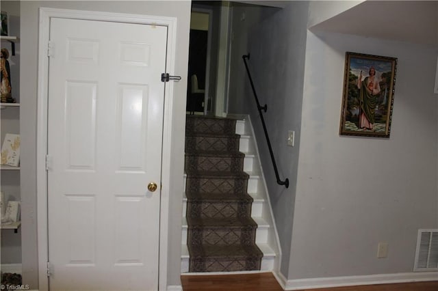 stairway featuring baseboards and visible vents