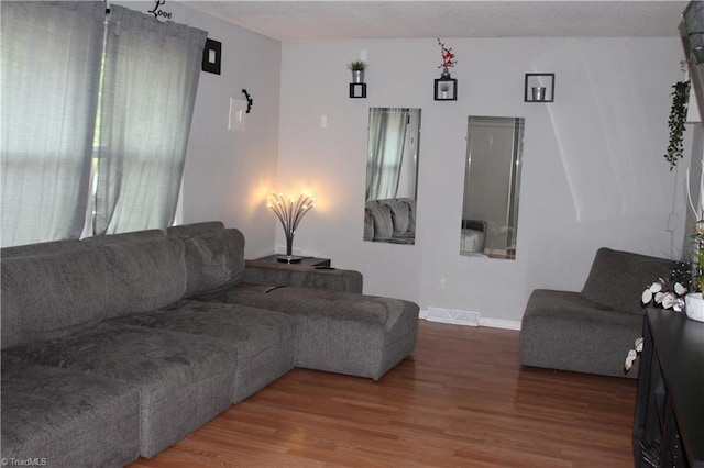 living room featuring baseboards, visible vents, and wood finished floors