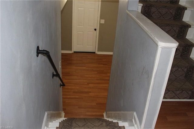 stairway with baseboards and wood finished floors