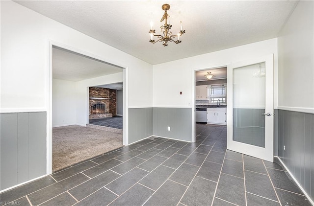 306 Pratt Rd, Dobson, NC 27017 - unfurnished dining area featuring a chandelier, wainscoting, a fireplace, a textured ceiling, and dark tile patterned flooring