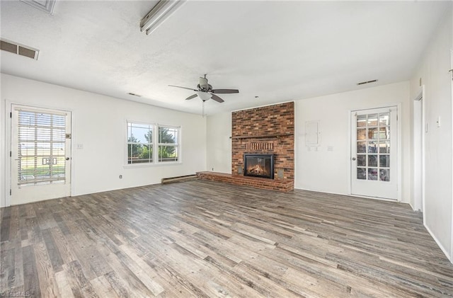 306 Pratt Rd, Dobson, NC 27017 - unfurnished living room with wood finished floors, a ceiling fan, a brick fireplace, and baseboard heating
