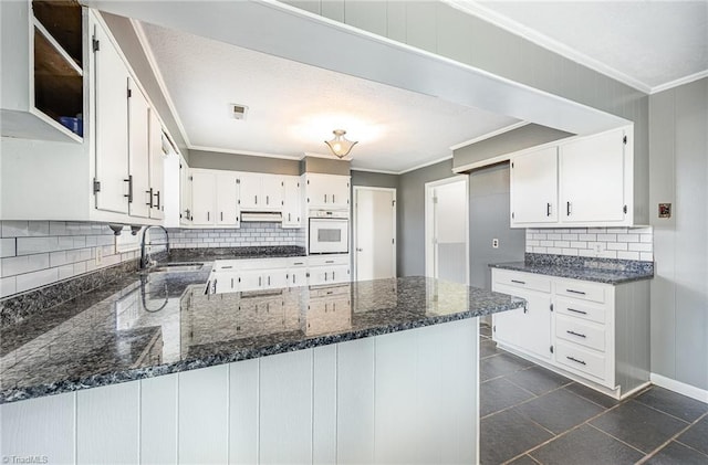 306 Pratt Rd, Dobson, NC 27017 - kitchen with oven, backsplash, a peninsula, ornamental molding, and white cabinetry