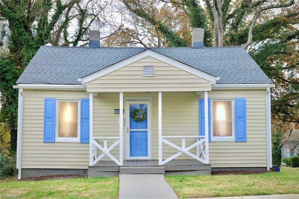 bungalow-style home with a front yard and covered porch