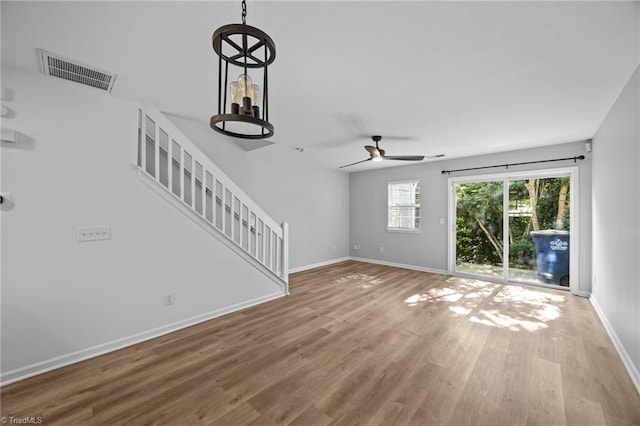 unfurnished living room featuring wood finished floors, stairs, baseboards, and a ceiling fan