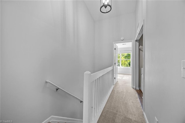 corridor featuring an upstairs landing, carpet floors, and baseboards