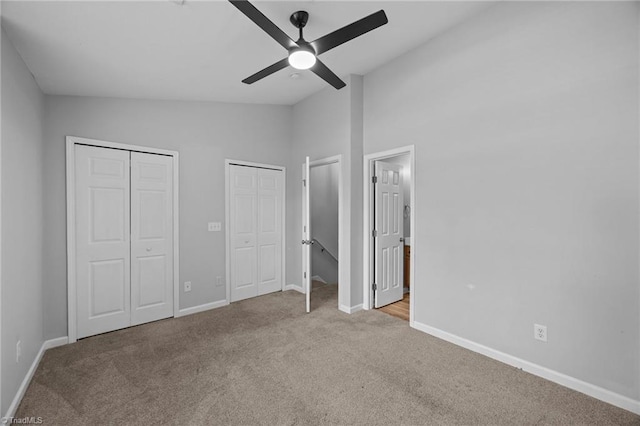 unfurnished bedroom featuring vaulted ceiling, carpet, multiple closets, baseboards, and ensuite bathroom