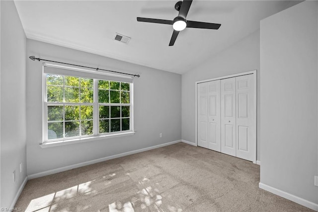 unfurnished bedroom featuring vaulted ceiling, carpet flooring, a closet, baseboards, and ceiling fan