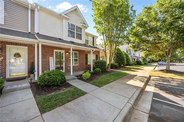 multi unit property with a porch, brick siding, and concrete driveway