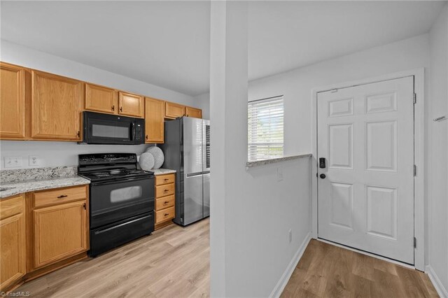 kitchen featuring black appliances, light wood-type flooring, baseboards, and light stone counters
