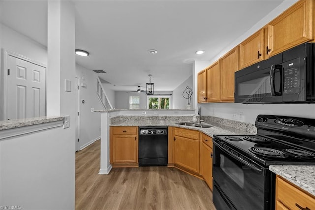 kitchen featuring black appliances, a sink, a ceiling fan, light wood-type flooring, and a peninsula