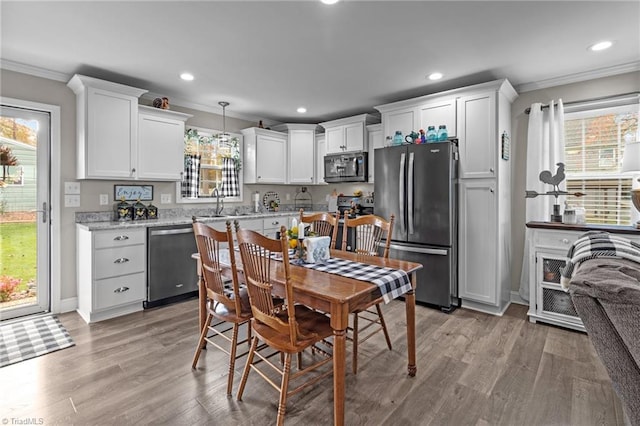 kitchen featuring stainless steel appliances, white cabinetry, hanging light fixtures, and a healthy amount of sunlight