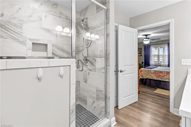 bathroom featuring hardwood / wood-style flooring, a shower with door, and ceiling fan