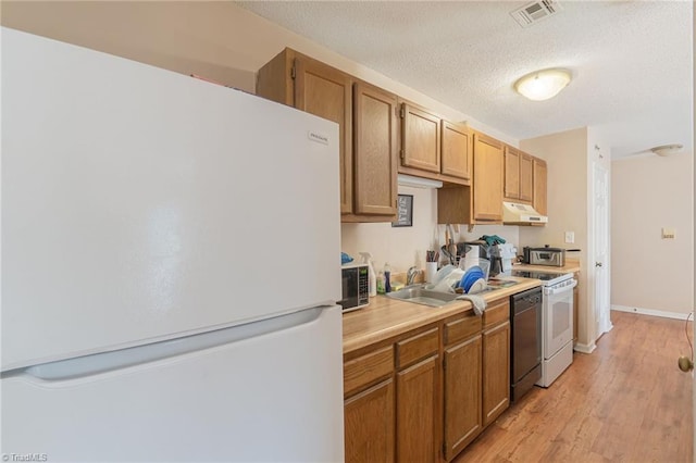 kitchen featuring white appliances, light hardwood / wood-style flooring, sink, and a textured ceiling