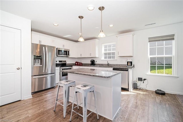 1026 Baileys Chapel Rd, Advance, NC 27006 - kitchen featuring appliances with stainless steel finishes, light wood finished floors, a center island, white cabinetry, and recessed lighting