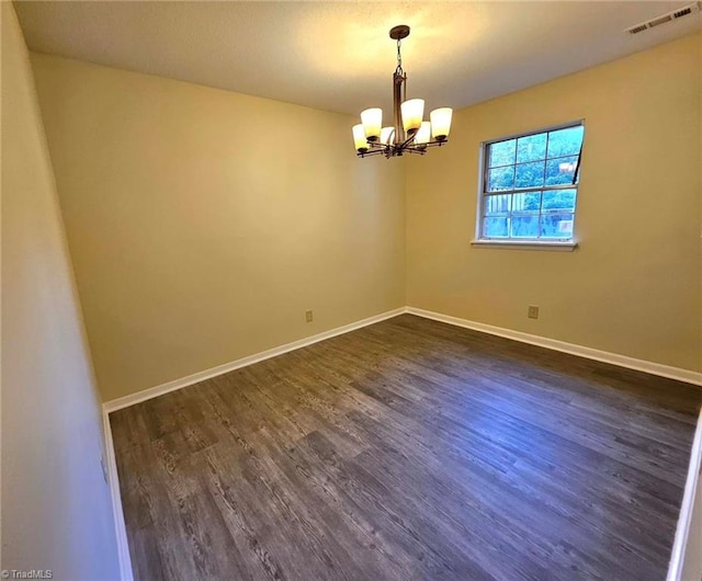 empty room featuring a chandelier and dark hardwood / wood-style flooring