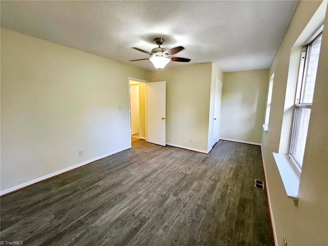 spare room with ceiling fan, a textured ceiling, dark hardwood / wood-style flooring, and a wealth of natural light