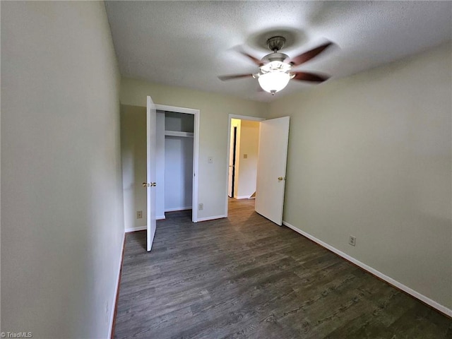 unfurnished bedroom featuring ceiling fan, a textured ceiling, a closet, and dark hardwood / wood-style floors