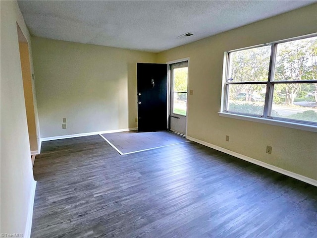 empty room featuring a textured ceiling and dark wood-type flooring