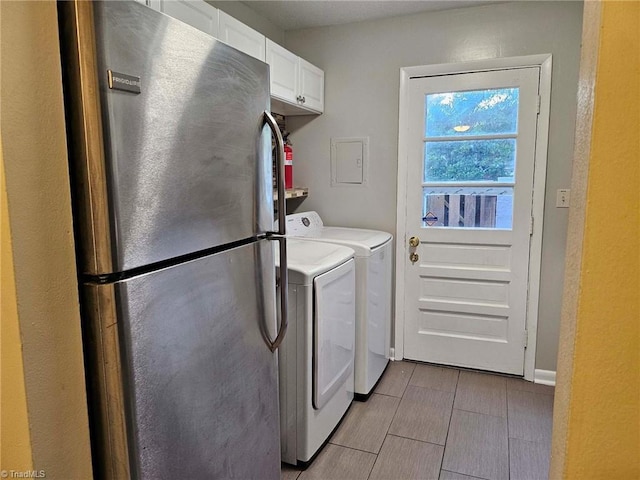 clothes washing area featuring washing machine and dryer and cabinets