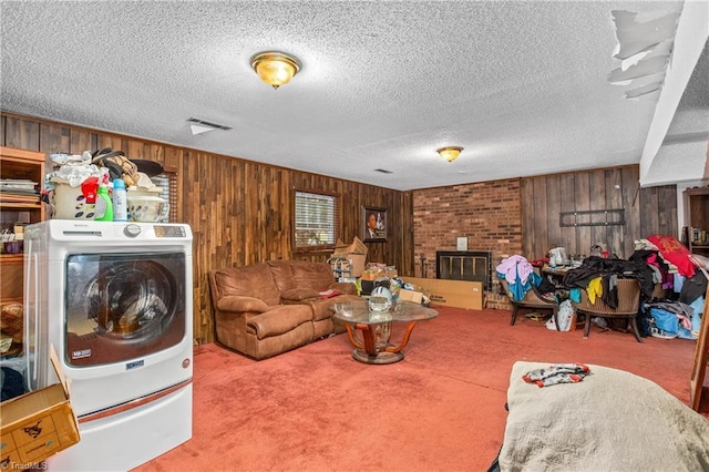 carpeted living room featuring wooden walls, visible vents, washer / clothes dryer, a textured ceiling, and a fireplace