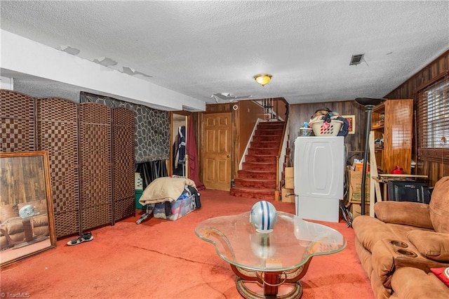 living area with carpet, visible vents, wood walls, a textured ceiling, and stairs