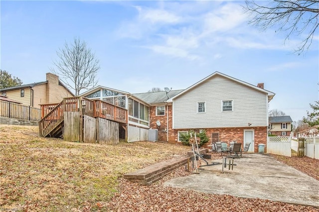 back of property with a patio, brick siding, fence, a sunroom, and stairs