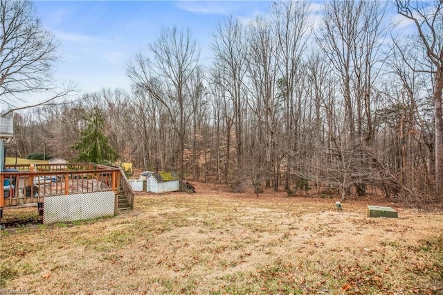 view of yard featuring a storage shed, an outdoor structure, and a wooden deck