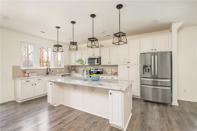 kitchen featuring appliances with stainless steel finishes, sink, white cabinets, a center island, and light stone countertops